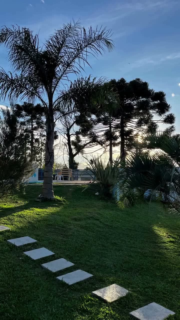Jardim da pousada ao entardecer, com palmeiras contra o céu