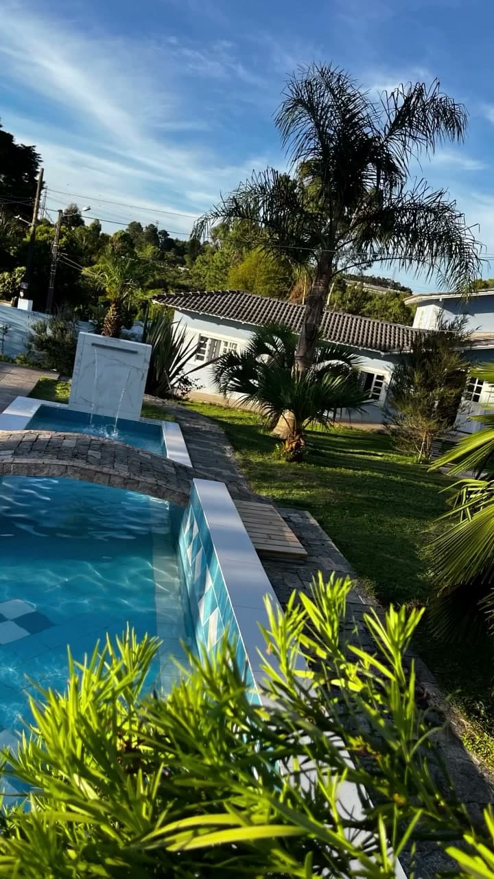 Piscina menor com cascata, cercada pelo jardim